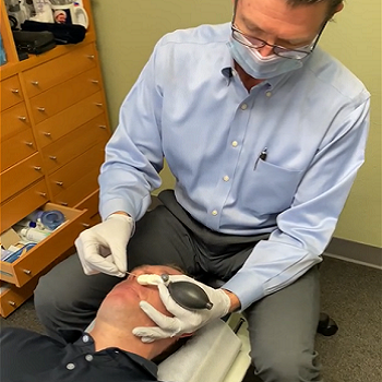 Dr. Olsen performing a cranial facial release on a patient, CFR, used to treat issues like breathing issues, breathing obstruction, vertigo/dizziness, breathing issues, post concussion, insomnia, mild traumatic brain injury, cognitive impairment, cognitive decline, headaches, migraines, TMJ, sleep issues, facial pain, concussion, and cranial nerve issues.